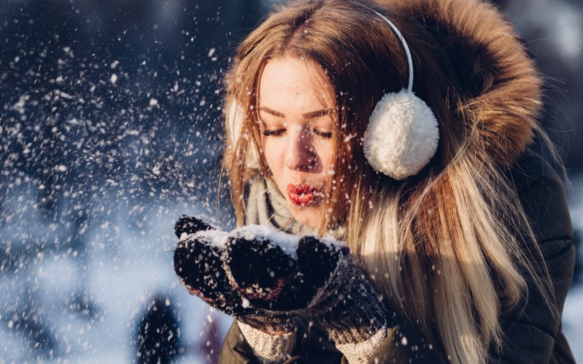 nainen puhaltaa lunta kämmenistään