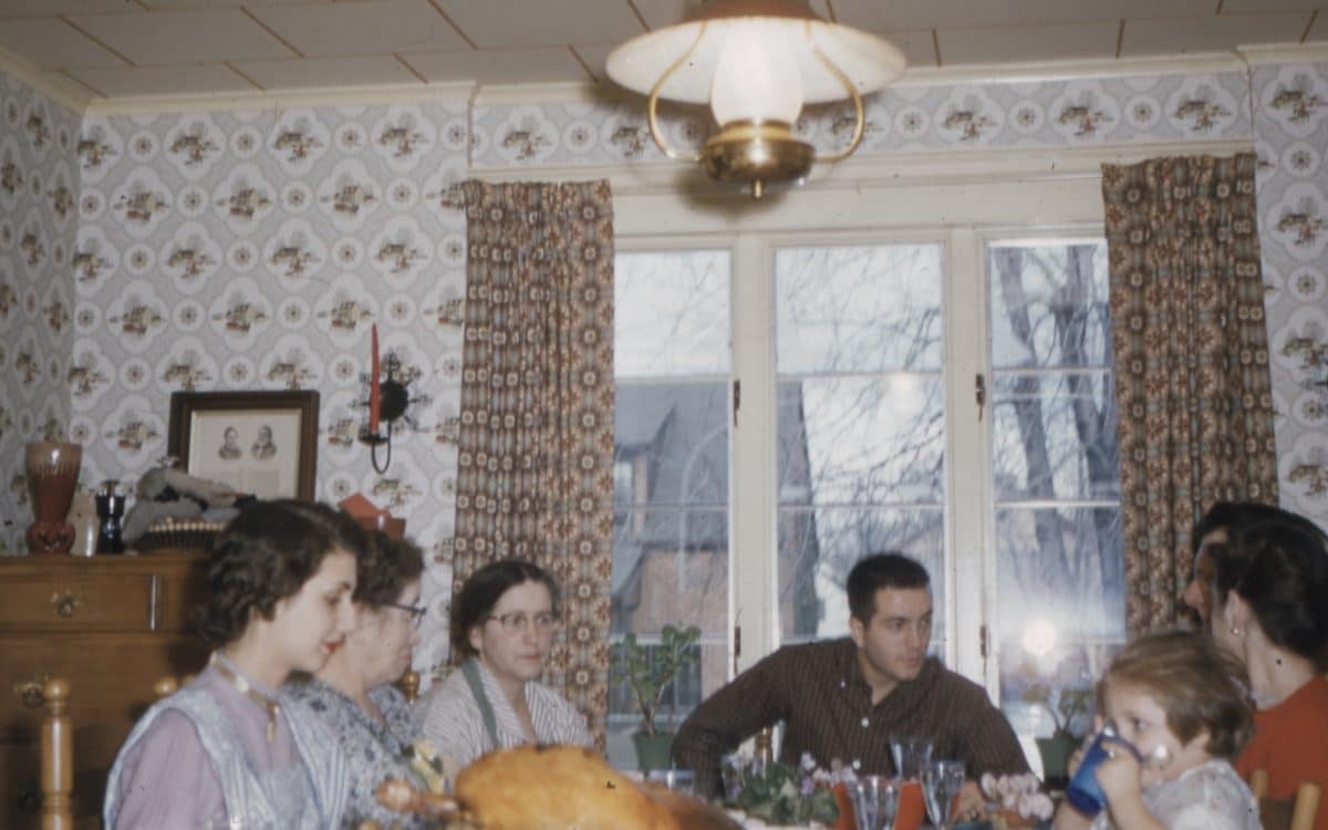 perhe koolla juhla-aterialla vanhanaikaisessa kodissa