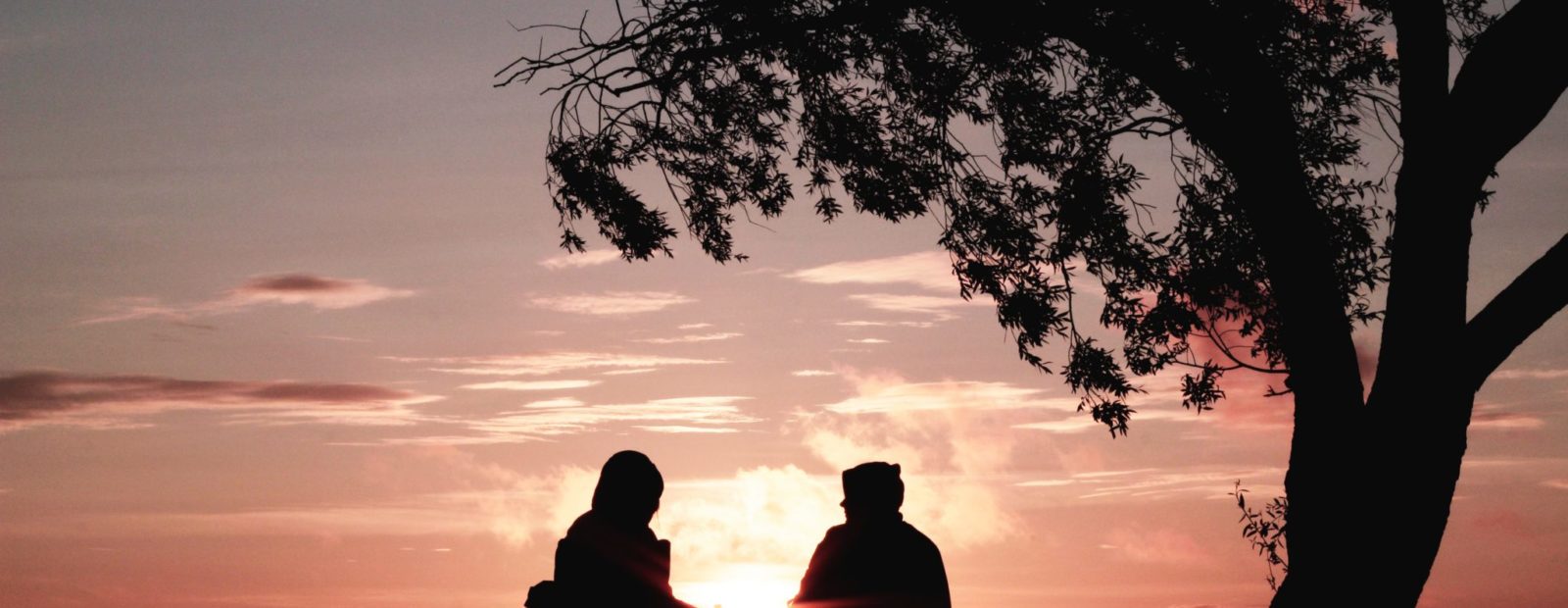 Ihmisiä istumassa auringonlaskun aikaan